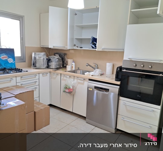 מטבח עם ארונות פתוחים, קופסאות קרטון ומכשירי חשמל